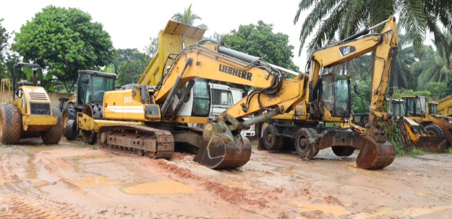 Excavators and rollers parked on red earth at the road site
