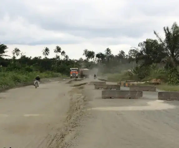 Road works on the Ikot Akpaden-Okoroete-Iko Road, with traffic and concrete drain sections beside the carriageway.