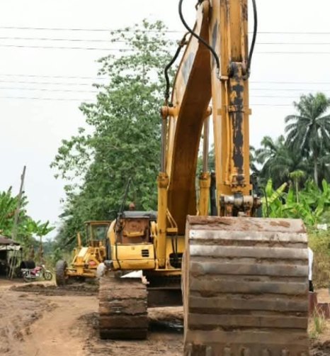 Yellow excavator on cleared earth beside the road