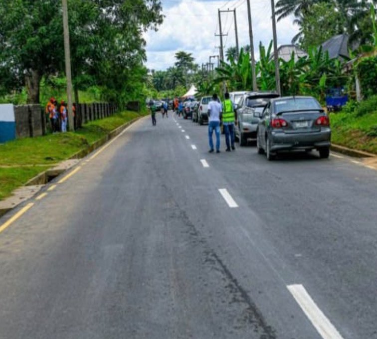 Newly asphalted road with lane markings and vehicles parked on the verge