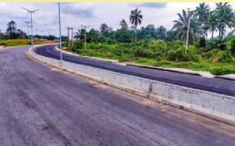 Curved asphalt carriageway with concrete median and street lights