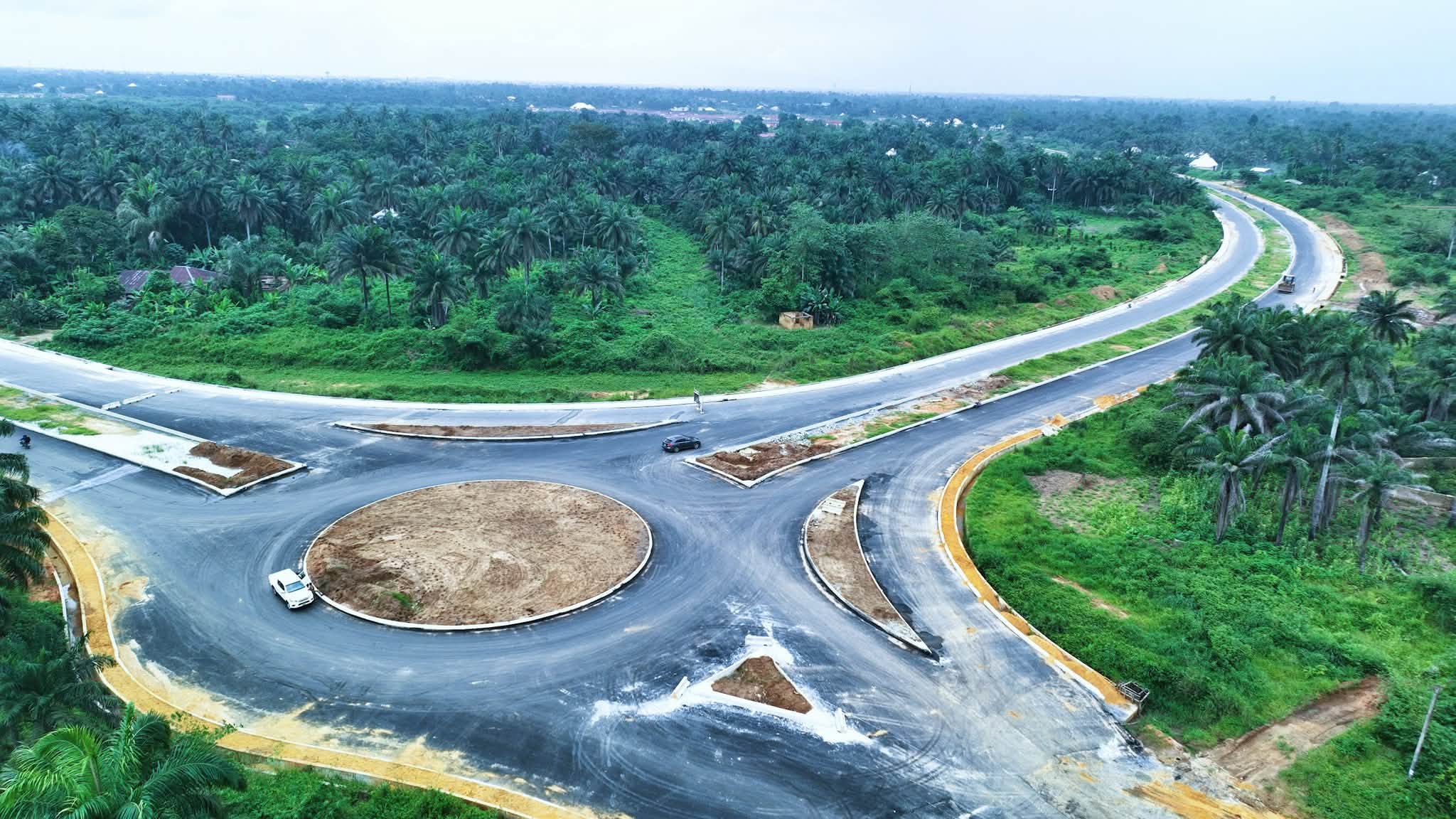 Aerial view of a newly paved roundabout with the dual carriageway curving through palm bush