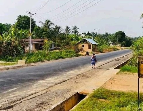 Surfaced road section with a concrete side drain beside it