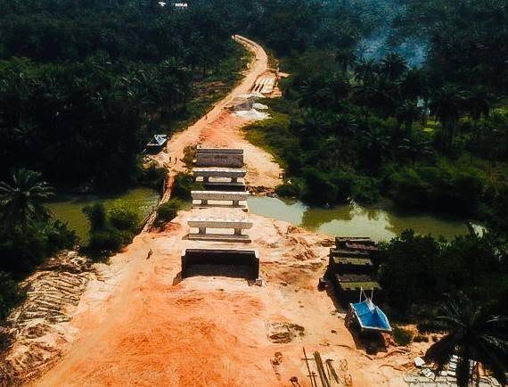 Aerial view of the early works: bridge piers and beams across the river and the cleared approach road