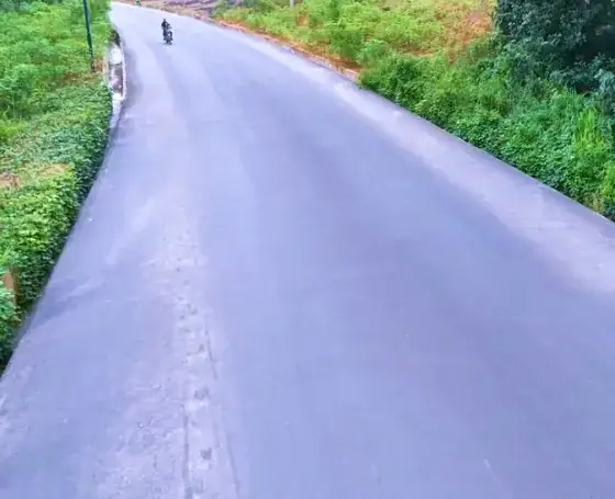 Newly surfaced road with grass verges.