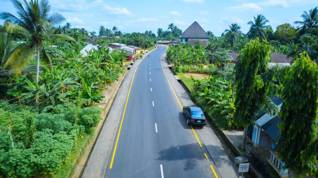 Finished asphalt road with lane markings and kerbs, a car driving on it
