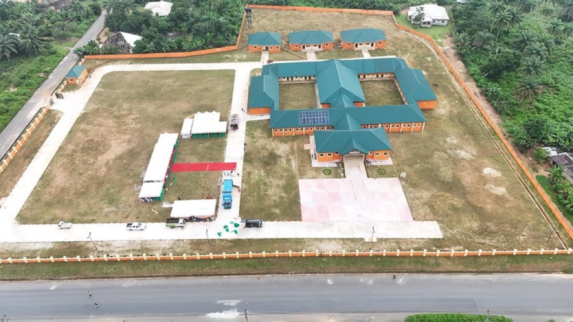The whole school compound from the air: classroom blocks, solar panels, staff houses, fence and access road
