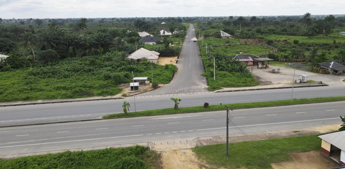 Road joining a wide main highway through farmland and villages