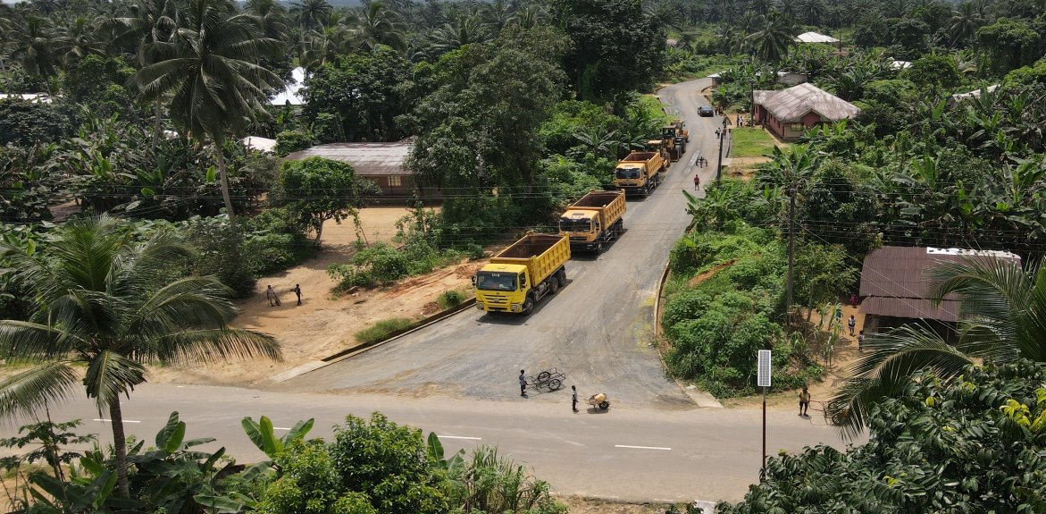 Tipper trucks on a bend of the road through the village