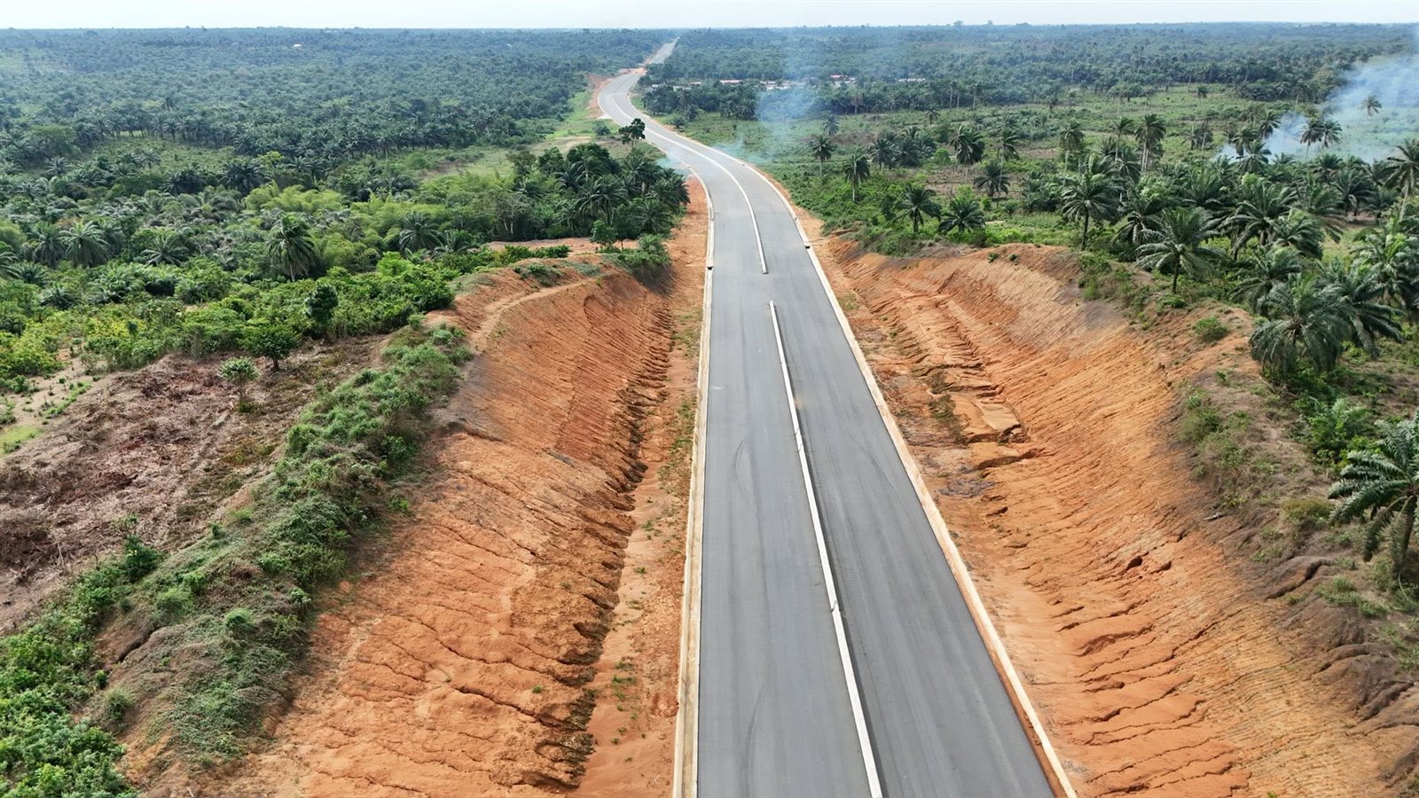 Long aerial view of the asphalted dual road through a deep earth cutting