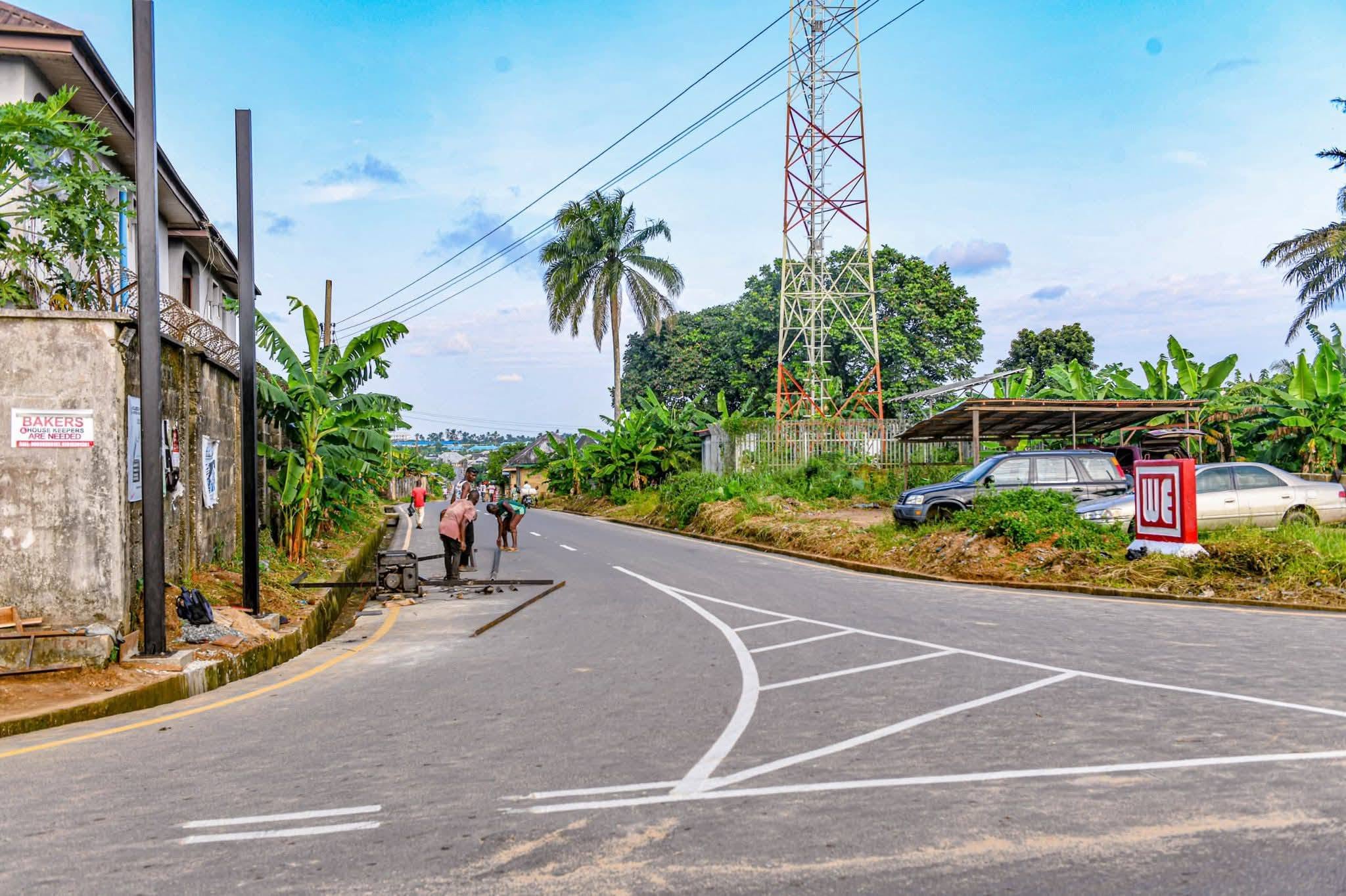 Road junction in Oron with fresh markings, side drain and workers fixing street light poles