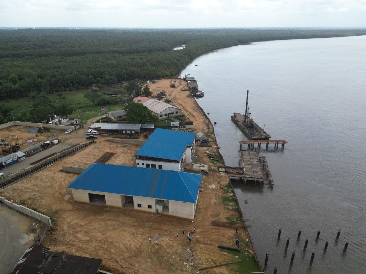 Blue-roofed warehouse and terminal buildings beside the jetty and river