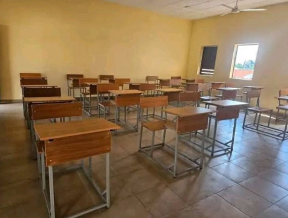 Empty classroom with rows of new desks and tall windows