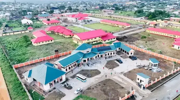 Aerial view of a walled compound of teal and pink-roofed buildings in Oron.