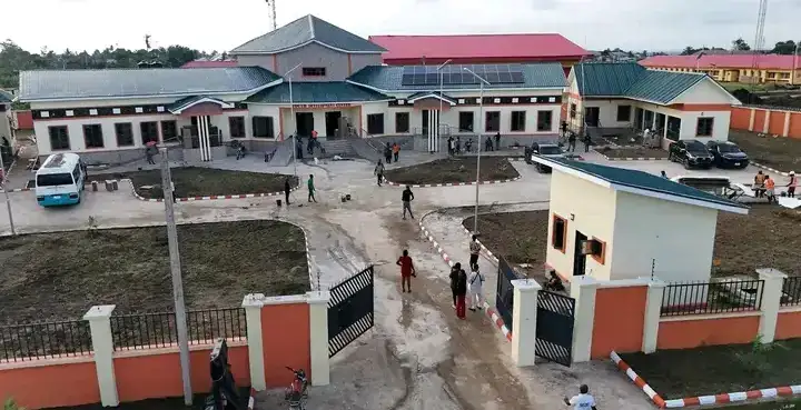 Ground view of a walled compound with teal-roofed buildings, Oron.