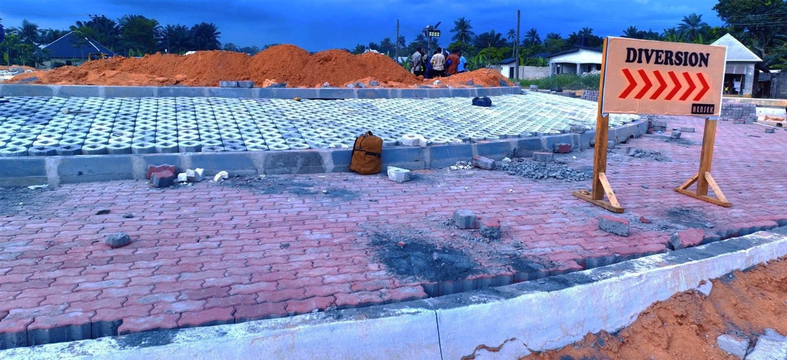 Interlocking paving and grass pavers being laid at a junction beside a diversion sign