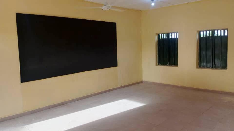 Inside a new classroom with a chalkboard, tiled floor and ceiling fan
