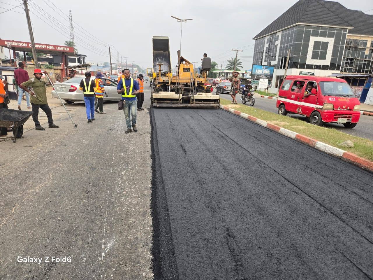 Paving machine laying a new asphalt lane on a busy road